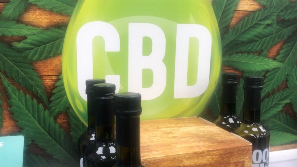 Bottles of CBD Oil in front of a sign that says CBD